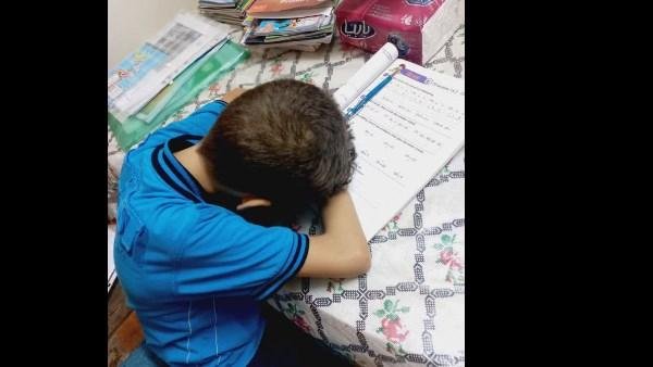 أم تنشر صورة تلميذ ابتدائي نام أثناء حل الواجبات: طفولته بتضيع وسط الكتب